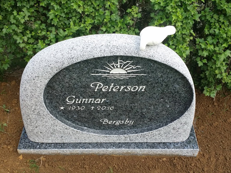 E059 finhuggen labrador granit med polerad spegel. Försänkt antikvit text och marmorduva på toppen.