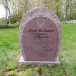 Modified E047 in finely honed red-flamed granite. Front edges rough-hewn to match the sides. Deep sandblasted text in a custom font; the decoration has been modified and is recessed with an antique white finish.