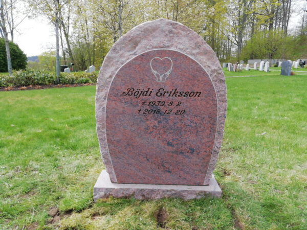 Modified E047 in finely honed red-flamed granite. Front edges rough-hewn to match the sides. Deep sandblasted text in a custom font; the decoration has been modified and is recessed with an antique white finish.