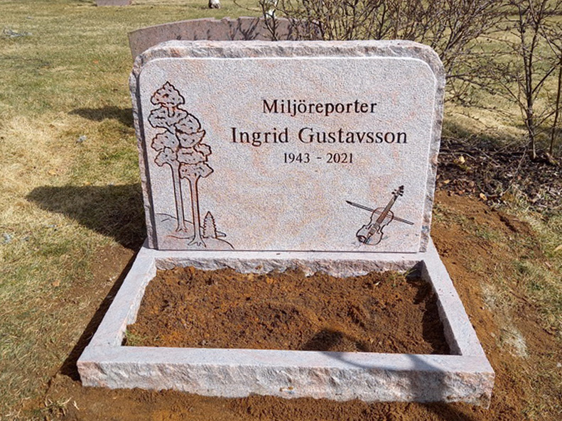 E046 i finhuggen rödflammig granit med råarbetat kantslag. Djupblästrad gravyr, dekorer med mattslipade detaljer, mattslipad blomlist med råarbetade sidytor.