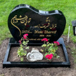 E061 in polished black granite with a polished flower border. Custom decorative motif and non-Latin characters in recessed, gilded engraving.