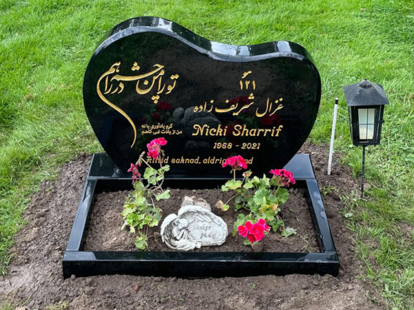 E061 in polished black granite with a polished flower border. Custom decorative motif and non-Latin characters in recessed, gilded engraving.