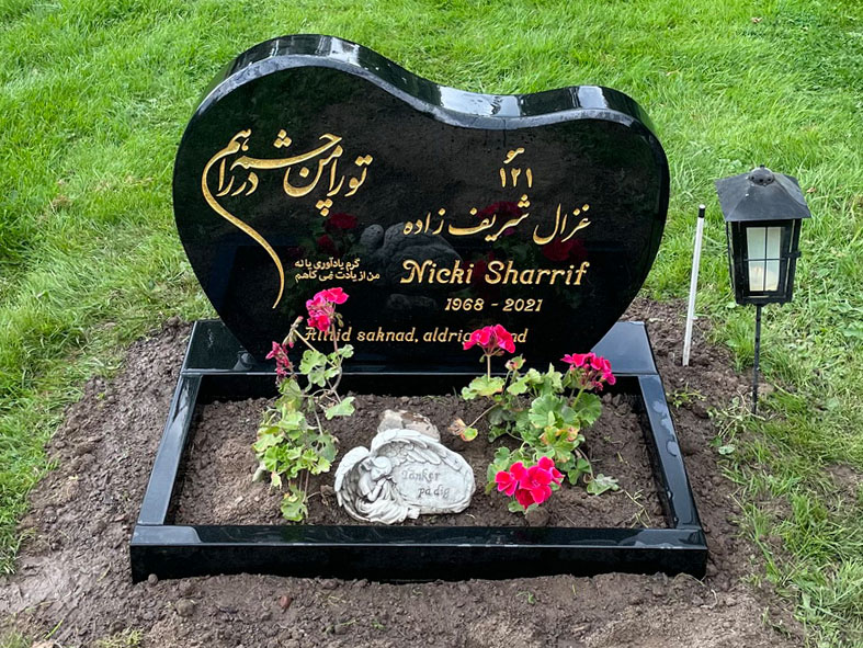 E061 in polished black granite with a polished flower border. Custom decorative motif and non-Latin characters in recessed, gilded engraving.