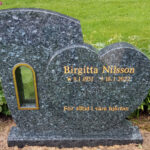 E044 in labrador granite. Recessed, gilded lettering and a bronze lantern.