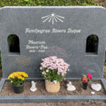 E046 i mörkgrå granit, anpassad i storlek och med två dekorationshål. Gravyr försänkt antikvit, polerad blomlist.