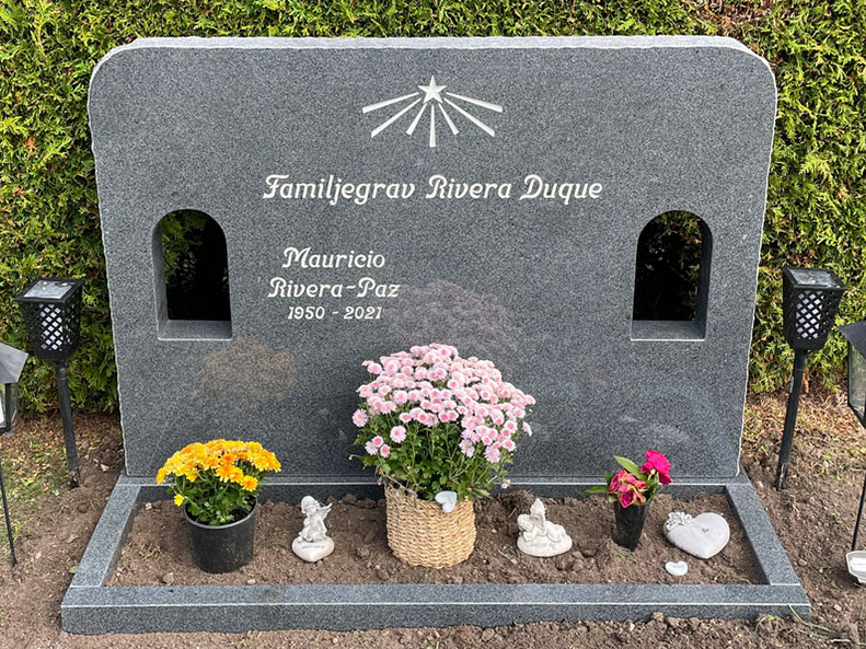 E046 i mörkgrå granit, anpassad i storlek och med två dekorationshål. Gravyr försänkt antikvit, polerad blomlist.