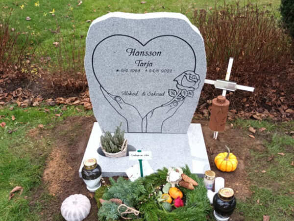 E016 in polished light gray granite with rough-worked side surfaces. All engraving is recessed and painted black. The stone is mounted on a planting base.