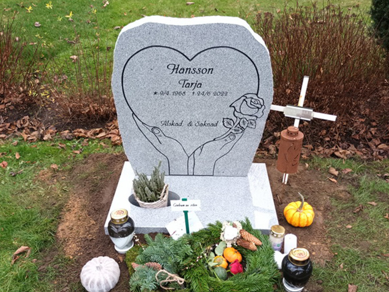 E016 in polished light gray granite with rough-worked side surfaces. All engraving is recessed and painted black. The stone is mounted on a planting base.