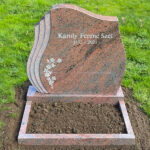 E078 in red-flamed granite, custom-sized. Polished flower border and recessed inscription painted antique white.