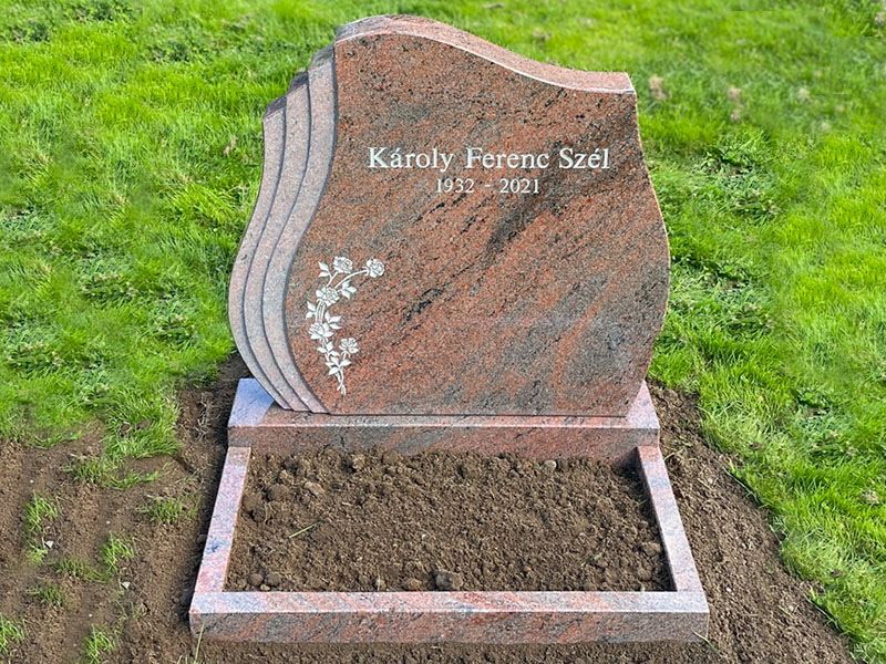 E078 in red-flamed granite, custom-sized. Polished flower border and recessed inscription painted antique white.