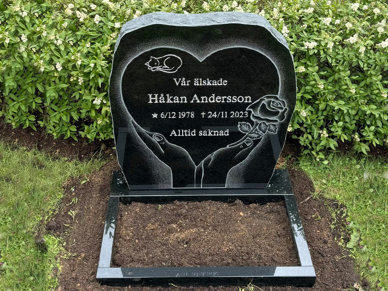E016 in black granite with a polished flower border. The large decorative motif is recessed and shadow-carved, while the remaining engraving is recessed and painted silver.