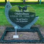 E080 in green-grey granite. Polished flower border, recessed black decoration, and recessed antique white text.