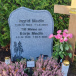 E015 i mörkgrå granit. Gravyren är upphöjd polerad, resten av framsida är finhuggen med ett råarbetat kantslag.