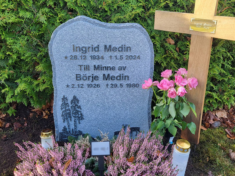 E015 i mörkgrå granit. Gravyren är upphöjd polerad, resten av framsida är finhuggen med ett råarbetat kantslag.