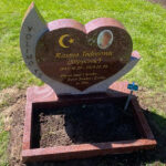 E080 in Indian red granite. Raised lettering on the side, recessed gilded engraving within the heart, polished flower border, porcelain photo.