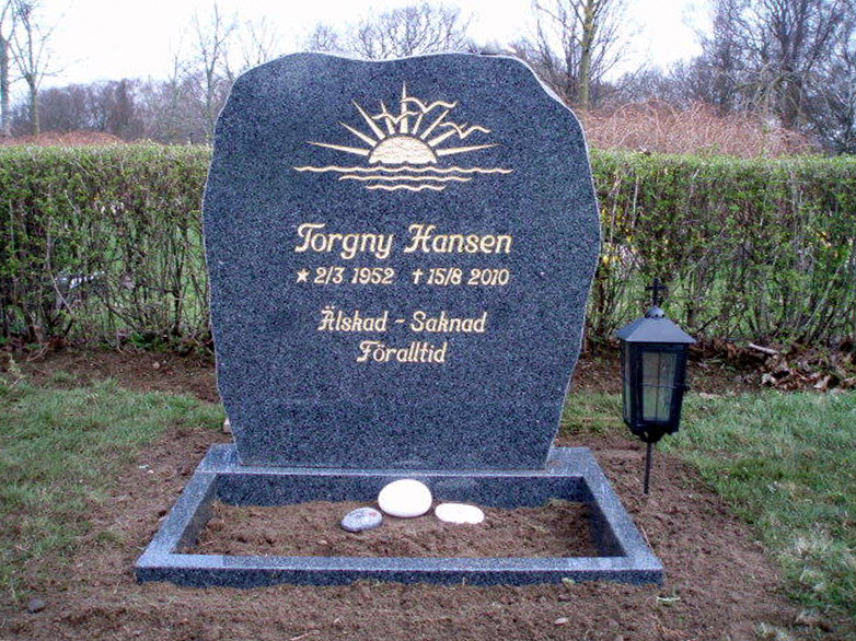 E016 in polished dark gray granite with rough-worked side surfaces. The engraving is recessed and gilded, the flower border is polished, and a marble dove imounted on the top.