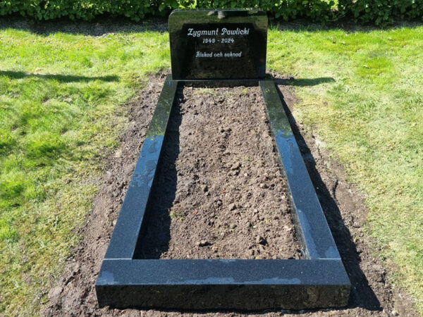 E046 i polerad svart granit. Försänkt antikvit gravyr, bredare sockel och en polerad gravram.