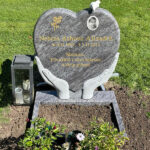 E005 in Indian blue-gray granite with a flower ledge, porcelain photo, and marble dove. The engraving is recessed and gilded.