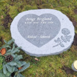 EN114 in fine-polished and fine-chiseled grey Kuru granite. Recessed antique-white text and raised fine-polished decoration.