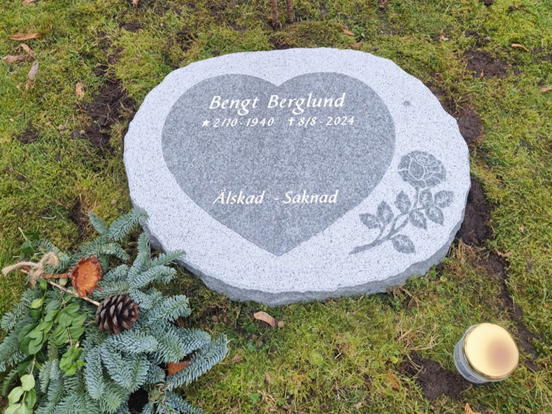 EN114 in fine-polished and fine-chiseled grey Kuru granite. Recessed antique-white text and raised fine-polished decoration.