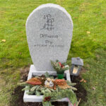 EN117 i flammad grå Kurugranit. Mattslipad blomlist med råarbetade sidytor, gravyr djupblästrad med stenglans.