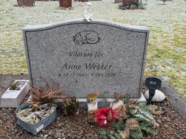 EN106 in flamed grey Bohus granite with matte-ground side surfaces. Deep-sandblasted engraving and a marble angel on the top.