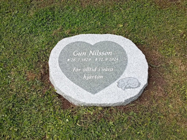 EN114 in fine-polished and fine-chiseled grey Kuru granite. Recessed antique-white text, raised decoration with the inside matte-polished.